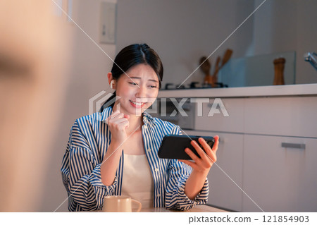 晚上在家用智慧型手機觀看運動比賽的年輕女性 121854903