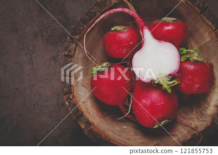 Radishes arranged on a wooden cutting board showcasing vibrant colors and textures 121855753
