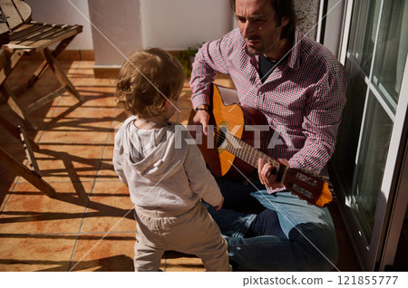 Outdoor bonding session with a guitar between an adult and a child 121855777