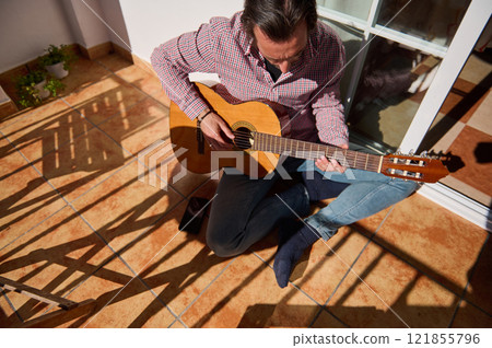 Man playing guitar at home on a sunny day 121855796