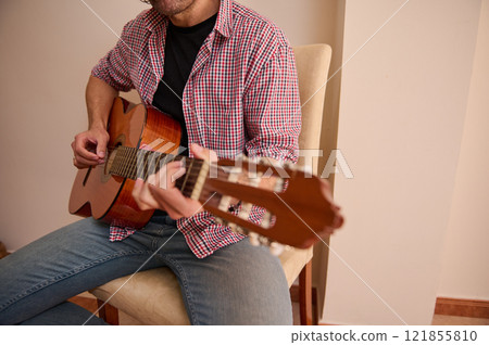 Man playing an acoustic guitar indoors wearing casual clothing Man playing an acoustic guitar indoors wearing casual clothing 121855810