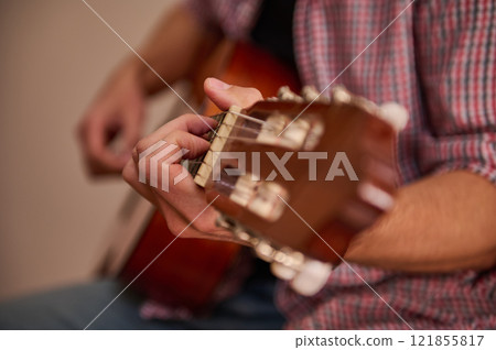 Hand playing an acoustic guitar in a close-up side shot Hand playing an acoustic guitar in a close-up side shot 121855817