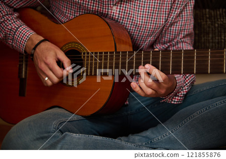 Close-up of hands gently playing an acoustic guitar on a relaxed setting Close-up of hands gently playing an acoustic guitar on a relaxed setting 121855876