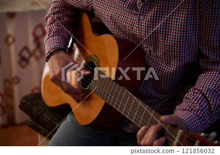 Close-up of hands playing a classical guitar indoors 121856032