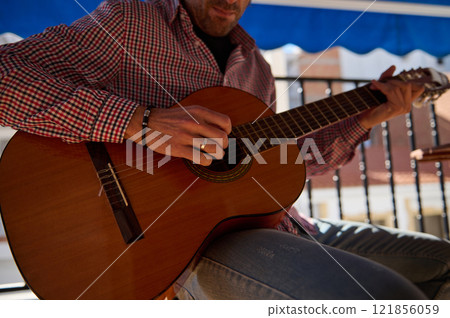Man playing acoustic guitar outdoors on a sunny day Man playing acoustic guitar outdoors on a sunny day 121856059