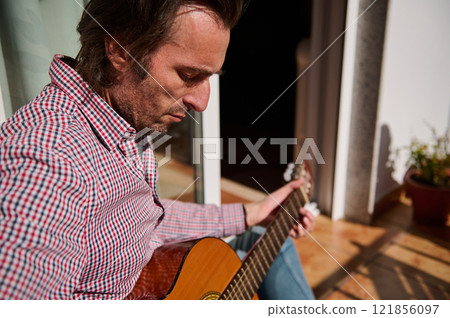 Man playing an acoustic guitar outdoors on a sunny day Man playing an acoustic guitar outdoors on a sunny day 121856097