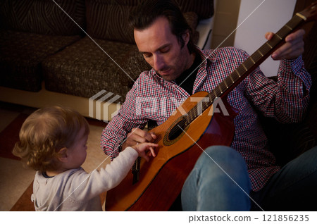 Father and child bonding through music and guitar playing at home 121856235