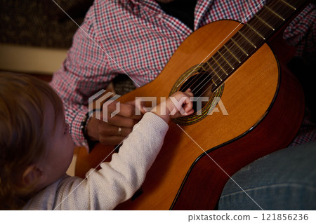Child and parent bonding through acoustic guitar music in warm home setting Child and parent bonding through acoustic guitar music in warm home setting 121856236