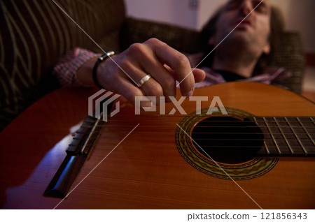 Man playing acoustic guitar with focus on his hand and strings 121856343