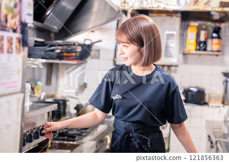 A female kitchen staff member working in the kitchen of an izakaya A female kitchen staff member working in the kitchen of an izakaya 121856363