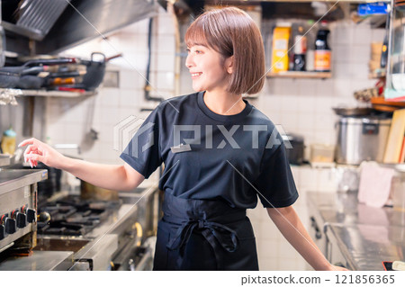 A female kitchen staff member working in the kitchen of an izakaya 121856365