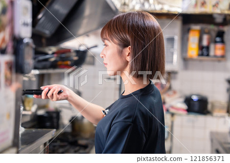 A female kitchen staff member working in the kitchen of an izakaya 121856371