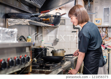 A female kitchen staff member working in the kitchen of an izakaya 121856373