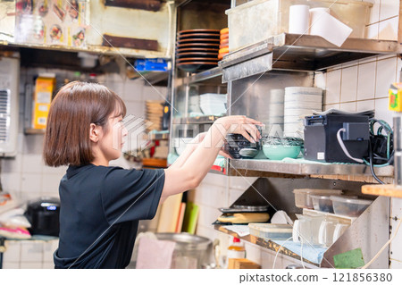 A female kitchen staff member working in the kitchen of an izakaya 121856380