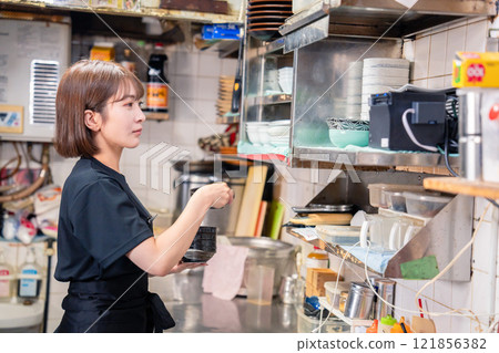 A female kitchen staff member working in the kitchen of an izakaya 121856382