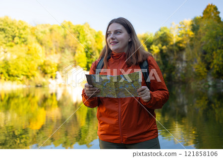 Traveling Happy Caucasian woman with backpack walking on path the mountain forest looking at the camera and map. Summer holiday and vacation trip Traveling Happy Caucasian woman with backpack walking on path the mountain forest looking at the camera and map. Summer holiday and vacation trip 121858106
