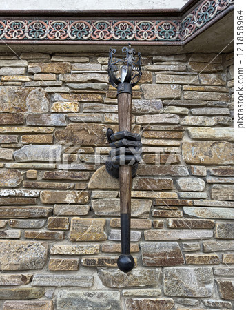 Unique Wall Sculpture Featuring a Hand Holding a Staff on a Stone Wall Unique Wall Sculpture Featuring a Hand Holding a Staff on a Stone Wall 121858964