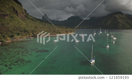 Turquoise water of Opunohu bay with sailboats yachts and catamarans anchoring near shore under a cloudy sky with lush green mountains in background, Moorea, French Polynesia. Wild nature paradise Turquoise water of Opunohu bay with sailboats yachts and catamarans anchoring near shore under a cloudy sky with lush green mountains in background, Moorea, French Polynesia. Wild nature paradise 121859193