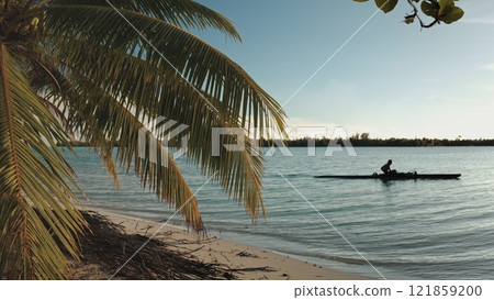 Palm trees frame a Polynesian fisherman paddling a traditional va'a outrigger canoe at sunset in the tranquil lagoon of Maupiti, French Polynesia. Remote wild nature paradise, exotic summer travel Palm trees frame a Polynesian fisherman paddling a traditional va'a outrigger canoe at sunset in the tranquil lagoon of Maupiti, French Polynesia. Remote wild nature paradise, exotic summer travel 121859200