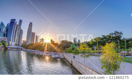 Sunset over Singapore skyscrapers skyline with white Anderson Bridge near esplanade park timelapse. 121860275