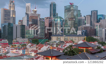 The Buddha Tooth Relic Temple comes alive at night in Singapore Chinatown day to night timelapse, with the city skyline in the background. 121860282