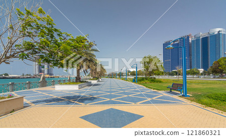 Corniche boulevard beach park along the coastline in Abu Dhabi timelapse hyperlapse with skyscrapers on background. Corniche boulevard beach park along the coastline in Abu Dhabi timelapse hyperlapse with skyscrapers on background. 121860321