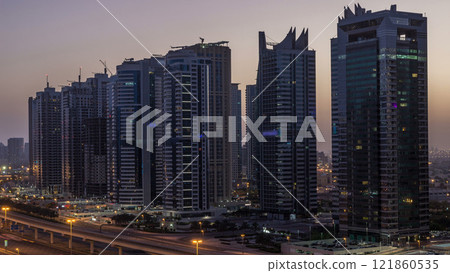 Aerial view of Jumeirah lakes towers skyscrapers night to day timelapse with traffic on sheikh zayed road. 121860535