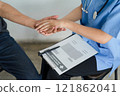 A nurse offers reassuring care by holding a patient's hand during a medical consultation, creating a supportive and empathetic atmosphere. 121862041