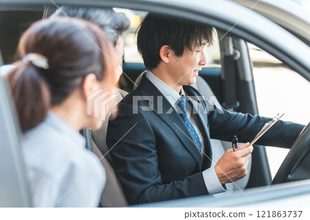 A young Asian male salesman serving customers who came to buy, assess and purchase a car A young Asian male salesman serving customers who came to buy, assess and purchase a car 121863737