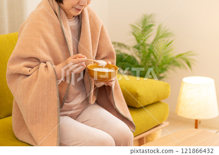 冬夜房間裡吃粥的中高級婦女 121866432