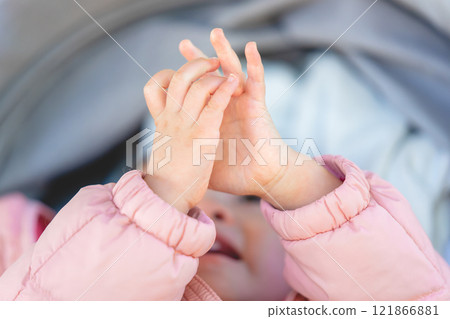 Hands of a toddler wearing a pink coat 121866881