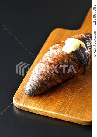 A slightly burnt black wasan on a cutting board photographed against a black background A slightly burnt black wasan on a cutting board photographed against a black background 121867382