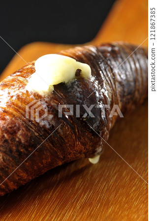 A slightly burnt black wasan on a cutting board photographed against a black background 121867385
