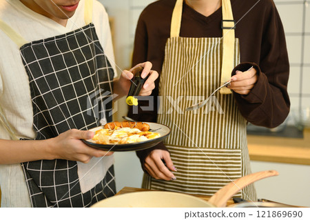 Young male gay couple preparing a delicious breakfast at counter in warm kitchen Young male gay couple preparing a delicious breakfast at counter in warm kitchen 121869690