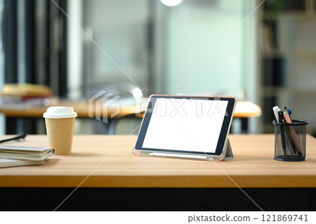Digital tablet with empty screen, coffee cup and pencil holder on wooden office desk Digital tablet with empty screen, coffee cup and pencil holder on wooden office desk 121869741