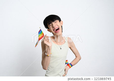 Cheerful young man holding rainbow pride flag over white background to celebrating LGBTQ pride 121869745