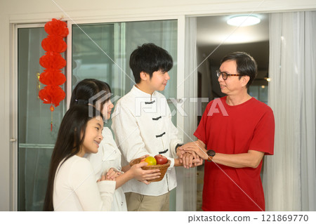 Young adult man offering a basket of fruits to elder as gesture of respect and gratitude during Chinese New Year 121869770