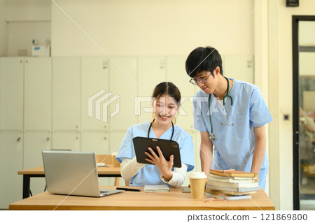 Two medical students in scrubs reviewing information on digital tablet in a classroom Two medical students in scrubs reviewing information on digital tablet in a classroom 121869800