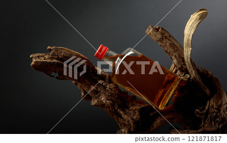 Bottle of whiskey on a old snags. 121871817