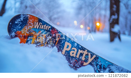 Snowboard on snowy ground with "Winter Party" text, blurred lights in background. Concept of winter sports and fun. 121872082
