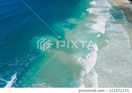 Surfers on surf spot and waves in blue ocean. Aerial view of surfers during surfing 121872233