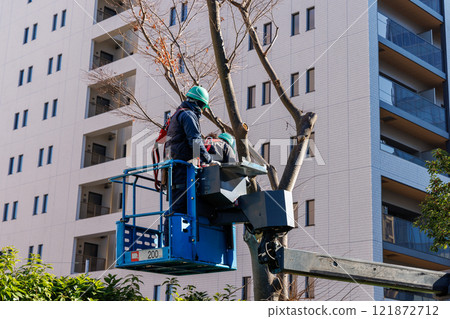 A worker trimming roadside trees on a high-altitude work vehicle 121872712