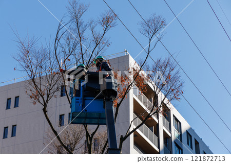 A worker trimming roadside trees on a high-altitude work vehicle A worker trimming roadside trees on a high-altitude work vehicle 121872713