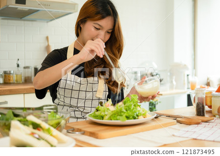 A woman enjoy making salad in the kitchen 121873495