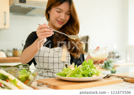A woman enjoy making salad in the kitchen A woman enjoy making salad in the kitchen 121873506