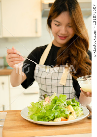 A woman enjoy making salad in the kitchen A woman enjoy making salad in the kitchen 121873507