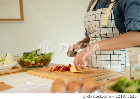 A woman cutting an apple in the kitchen 121873626