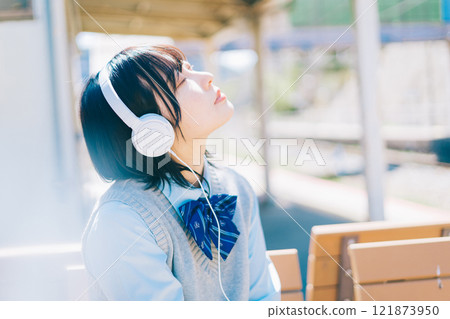High school girl listening to music on the platform of the station High school girl listening to music on the platform of the station 121873950