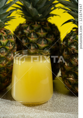 Pineapple juice in a glass among fresh pineapple fruit close-up. 121874347