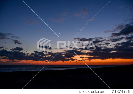 Beautiful crimson sunset and crescent moon over the sea Beautiful crimson sunset and crescent moon over the sea 121874596